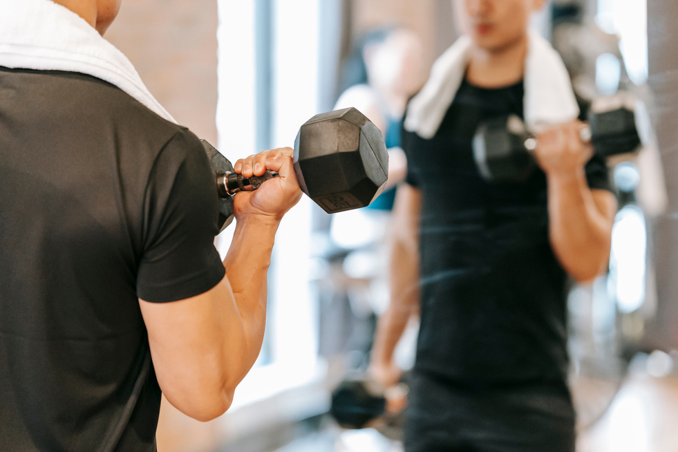 Crop man working out with weights in gym