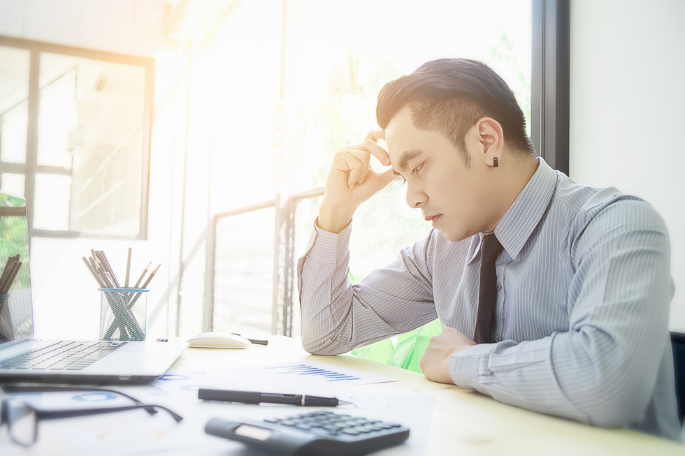 Businessman at Computer Covering His Face with His Hands